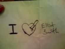 a hand drawn "I [heart with a knife in it] Elliott Smith on a piece of old paper